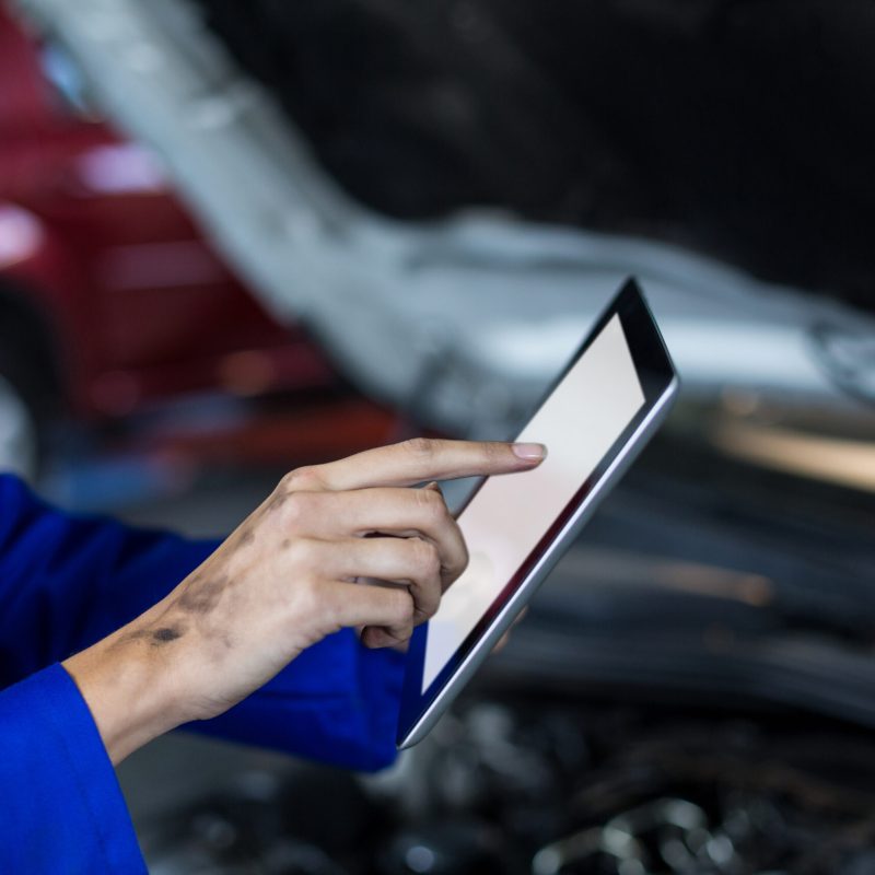 Hands of female mechanic using digital tablet in repair garage
